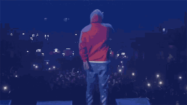 a man in an orange jacket is standing in front of a crowd