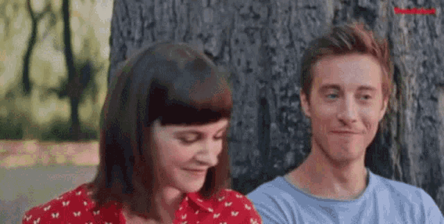 a man and a woman are sitting next to each other in a park .