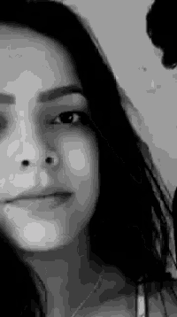 a black and white photo of a woman 's face with long dark hair .