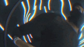 a man is standing in a room with purple lights behind him .