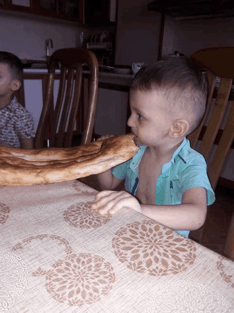 a little boy eating a piece of bread on a table