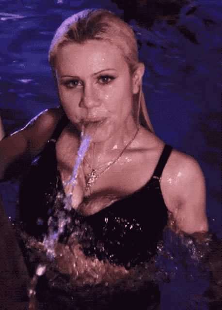 a woman in a black bra is drinking water from a bottle