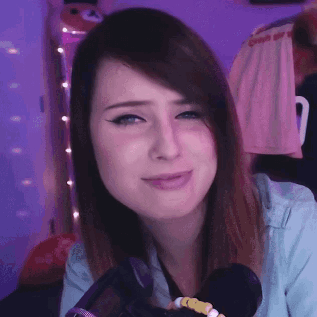 a woman is crying in front of a microphone while wearing a blue shirt .