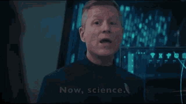 a man is standing in front of a computer screen and saying `` now , science '' .