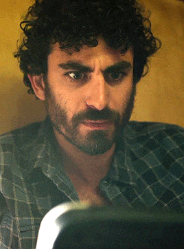 a man with curly hair and a beard looks at something