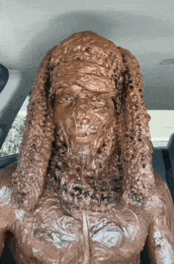 a statue of a man covered in chocolate is sitting in the back seat of a car