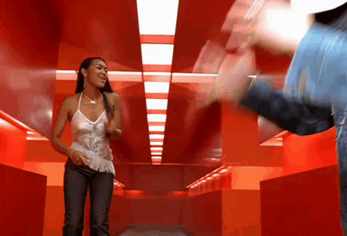a woman in a white tank top is standing in a red hallway