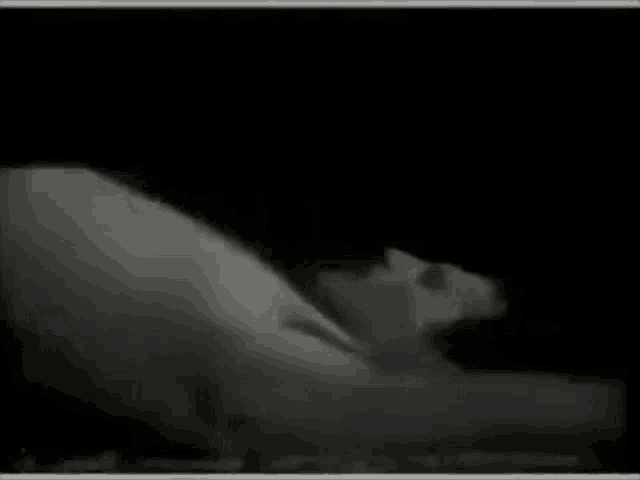 a black and white photo of a man laying on a bed with his arms outstretched .
