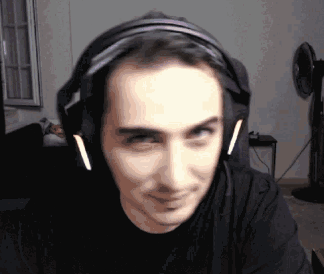 a man wearing headphones and a black shirt is smiling