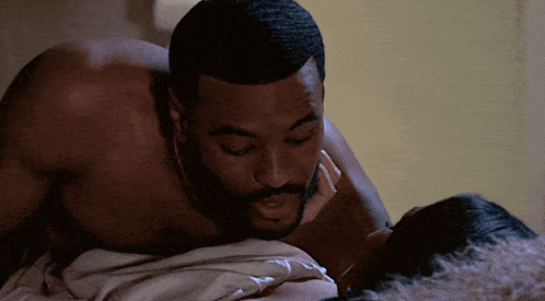a shirtless man kissing a woman on the neck
