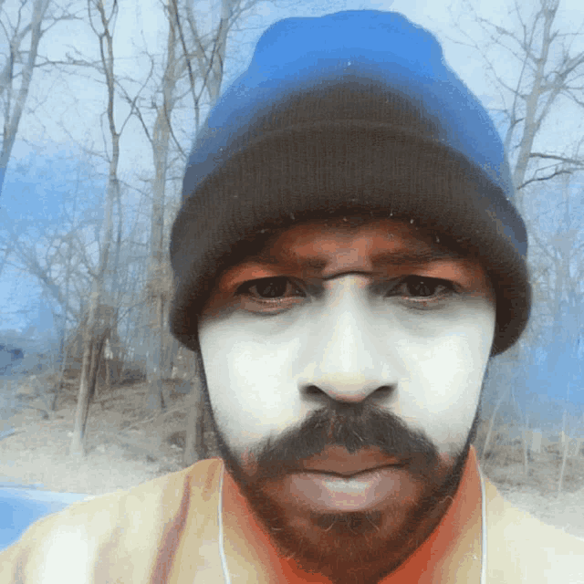 a man with a beard wearing a beanie and ear buds