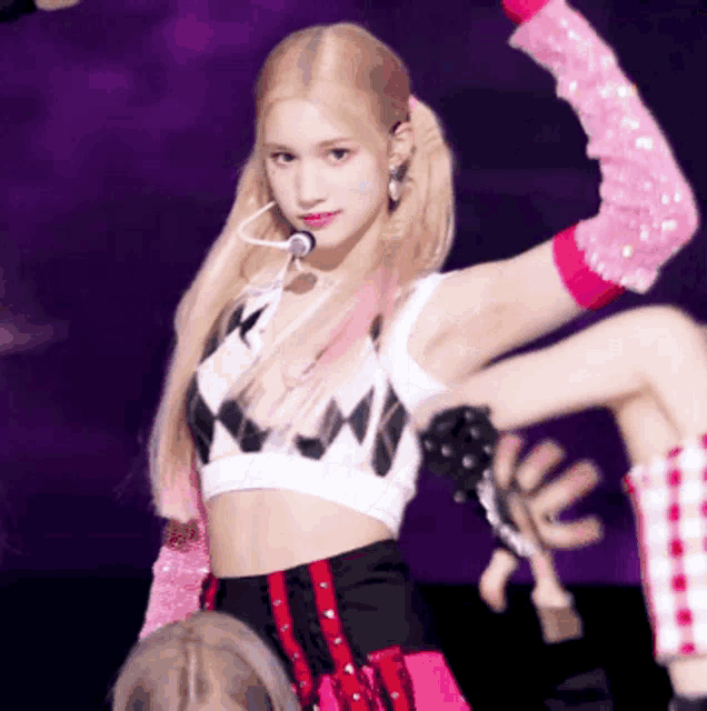 a woman in a crop top and pink sleeves is dancing on a stage .