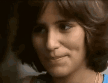 a close up of a woman 's face with brown hair and a blue shirt .