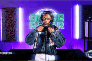 a man wearing headphones is standing in front of a neon sign that says on the radar