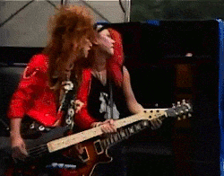 a man and a woman are playing guitars in a dark room
