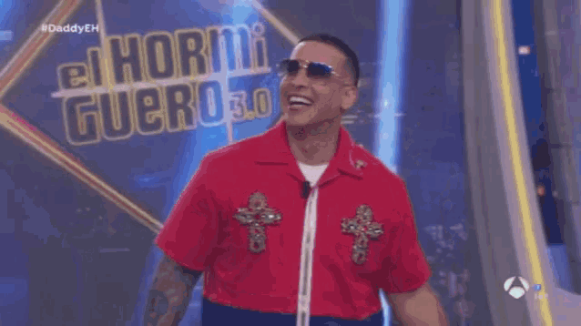 a man wearing sunglasses and a red shirt stands in front of a sign that says el hormiguero 3.0