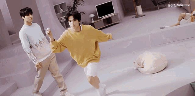 a man in a yellow sweater is holding a paper airplane next to another man in a blue sweater