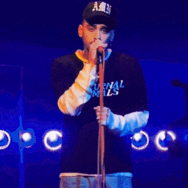 a man singing into a microphone wearing a shirt that says ' nocturnal animals ' on it