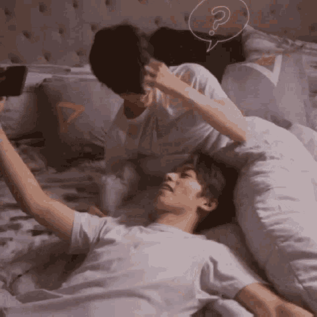 two men laying on a bed with a speech bubble with a question mark on it