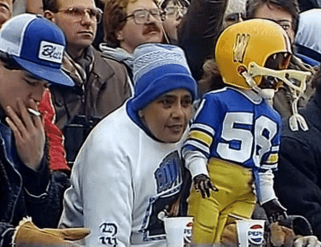 a man wearing a blue hat with the word black on it sits in a crowd of people