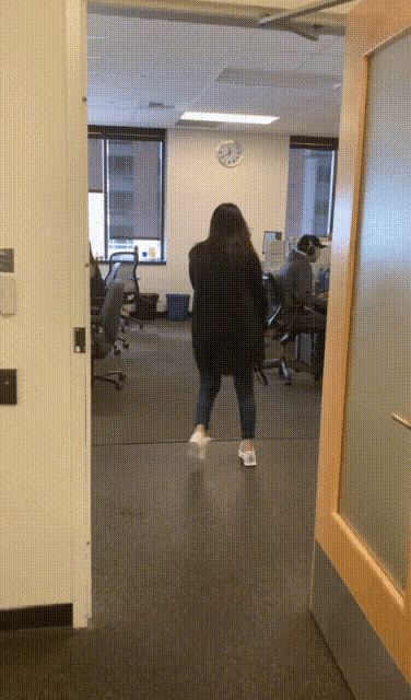 a woman stands in a hallway in front of a clock