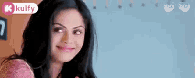 a woman is smiling and looking at the camera with a kulfy logo in the corner .