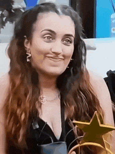 a woman in a black top is holding a gold star and smiling
