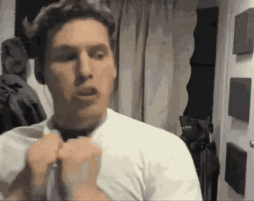 a man in a white shirt is adjusting his tie .