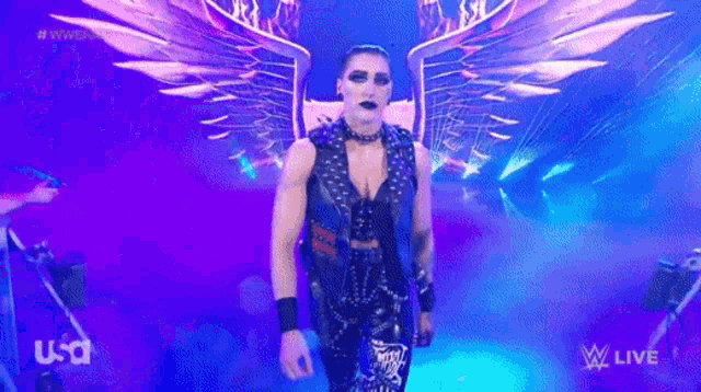 a wrestler with wings is walking down a stage .