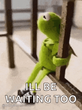 kermit the frog is sitting on a railing holding onto a railing .