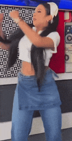 a woman in a white crop top and blue jeans dancing