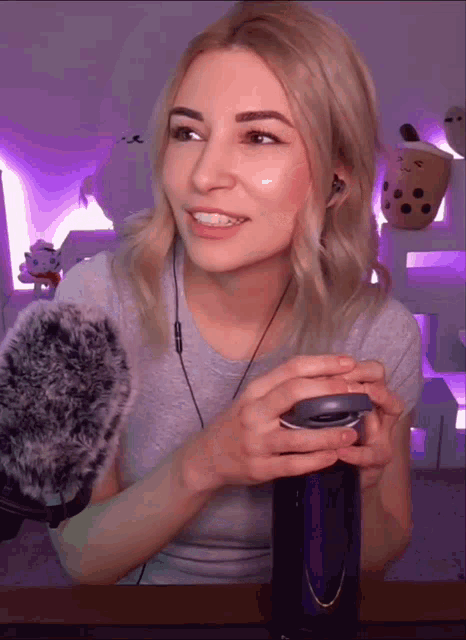 a woman wearing headphones is holding a purple bottle and smiling