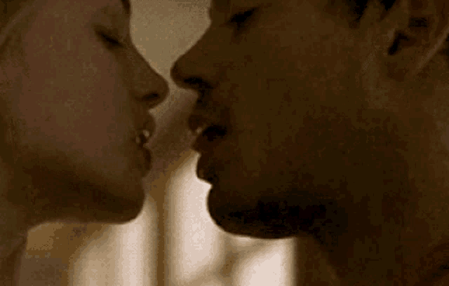 a man and a woman are kissing each other in a room .