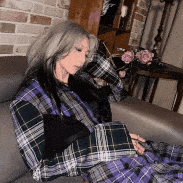 a woman laying on a couch with a plaid shirt on