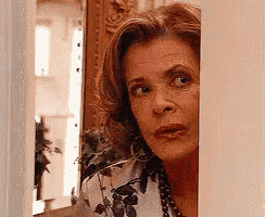 a woman peeking out from behind a wall and looking at the camera