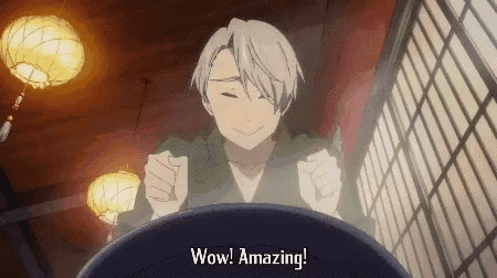 a man in a kimono is sitting at a table with his fist in the air and saying wow ! amazing .