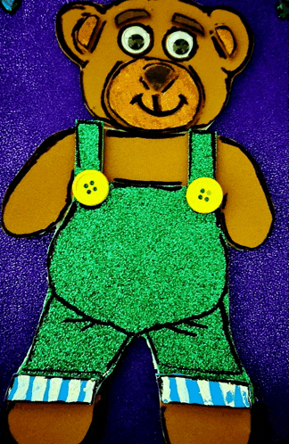 a brown teddy bear wearing green overalls with yellow buttons