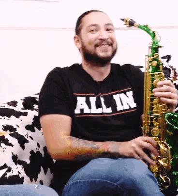 a man playing a saxophone and wearing a shirt that says all in