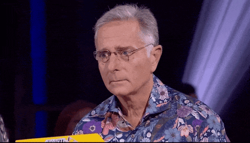 a man wearing glasses and a floral shirt is holding a yellow box with the word avanti on it