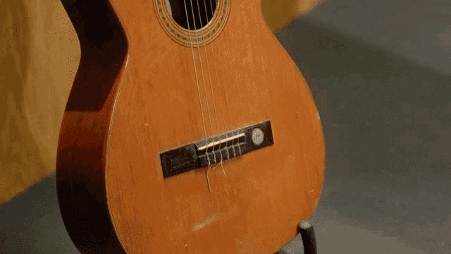 a close up of an acoustic guitar against a wooden wall