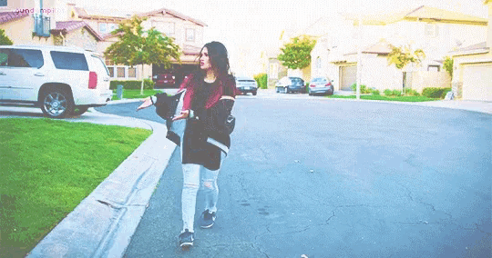 a woman is walking down a street in a residential neighborhood