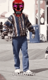 a man wearing a red skull mask and sunglasses is walking on a sidewalk .
