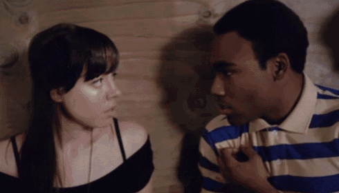 a man in a blue and white striped shirt is talking to a woman in a black top
