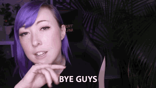 a woman with purple hair says bye guys in front of a palm tree