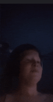 a woman 's face is visible in a dark room .