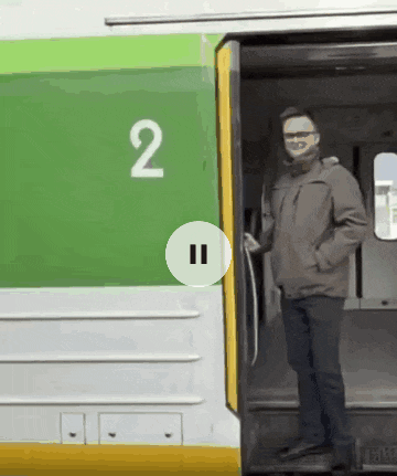 a man is standing in front of a green and white train with the number 2 on it