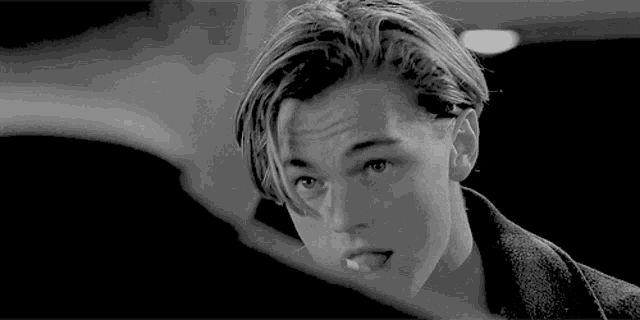 a black and white photo of a young man with his tongue out .
