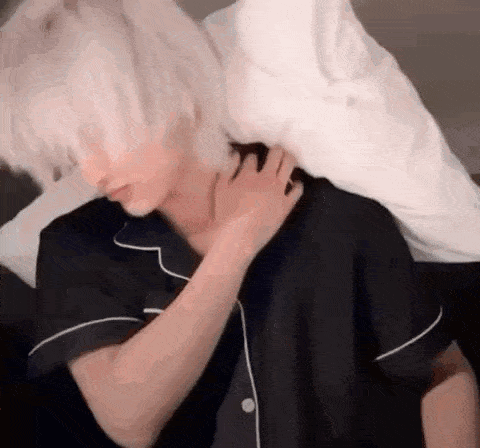 a man in pajamas is holding a white pillow over his neck .