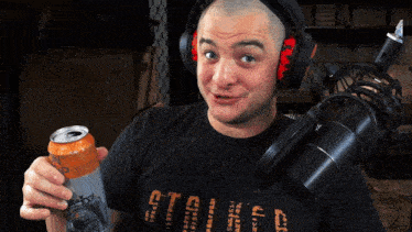 a man wearing headphones is holding a can of soda and a microphone in his hand