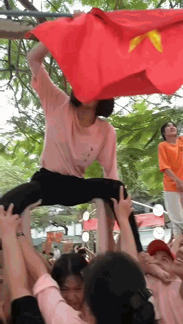 a woman in a pink shirt is being lifted in the air by a crowd
